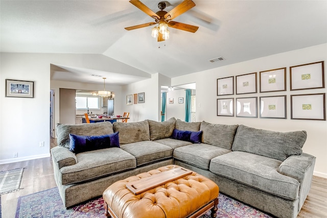 living room featuring ceiling fan with notable chandelier, light hardwood / wood-style floors, and lofted ceiling