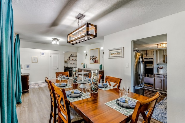 dining room featuring wood-type flooring and a textured ceiling