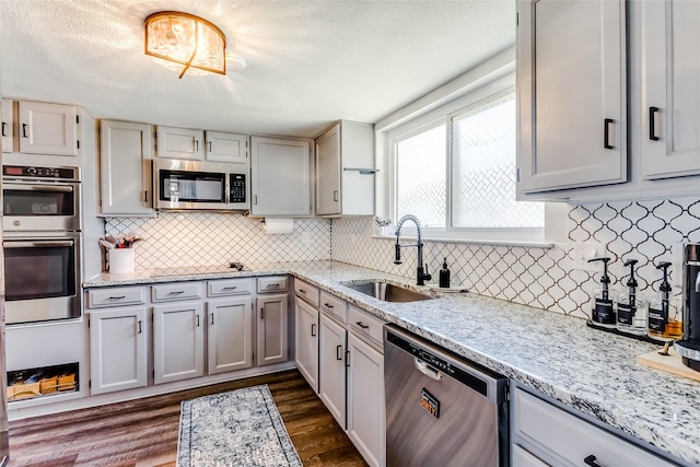 kitchen featuring appliances with stainless steel finishes, backsplash, dark wood-type flooring, and sink