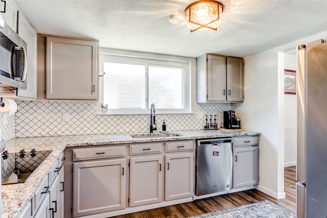 kitchen featuring light stone countertops, backsplash, stainless steel appliances, dark wood-type flooring, and sink