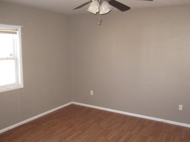 empty room featuring dark wood-type flooring, ceiling fan, and a healthy amount of sunlight