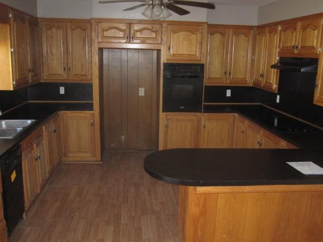 kitchen featuring kitchen peninsula, ceiling fan, sink, black appliances, and wood-type flooring