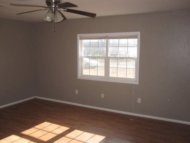 empty room with dark hardwood / wood-style floors and ceiling fan