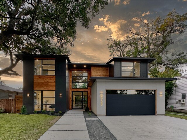 contemporary home featuring a garage and a lawn