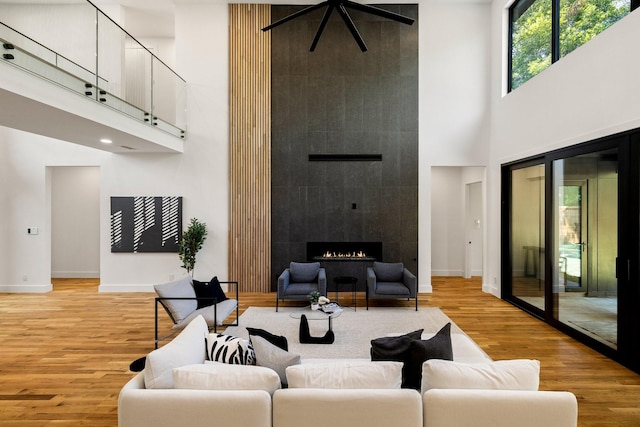 living room featuring a fireplace, light hardwood / wood-style flooring, and a high ceiling