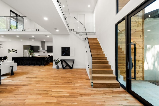 staircase with hardwood / wood-style flooring and a high ceiling