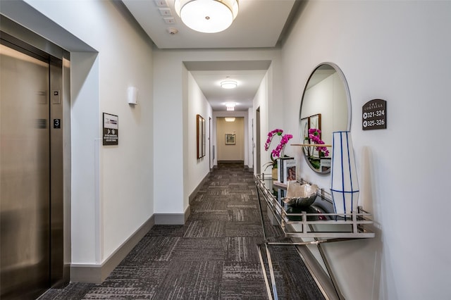 hallway featuring elevator and dark colored carpet