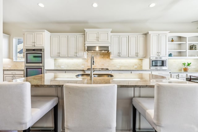 kitchen featuring a kitchen bar, light stone countertops, and appliances with stainless steel finishes