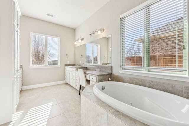 bathroom featuring tile patterned flooring, vanity, and a relaxing tiled tub