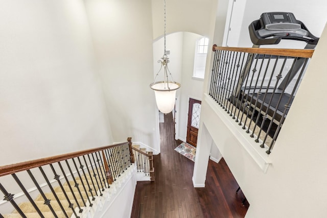 staircase featuring hardwood / wood-style floors, a notable chandelier, and a towering ceiling