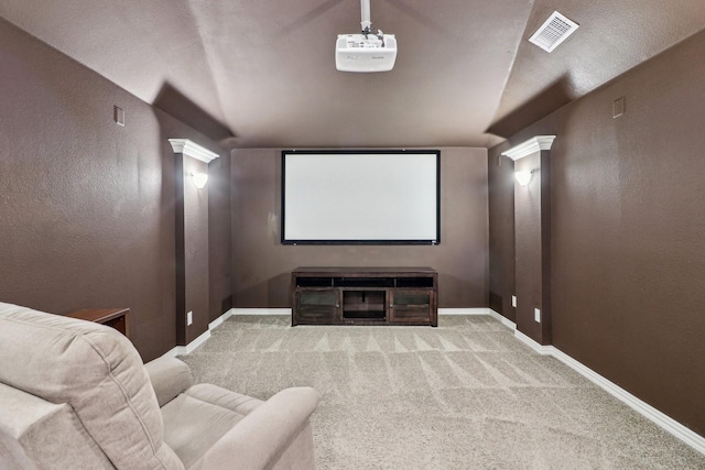 carpeted home theater room featuring decorative columns and vaulted ceiling