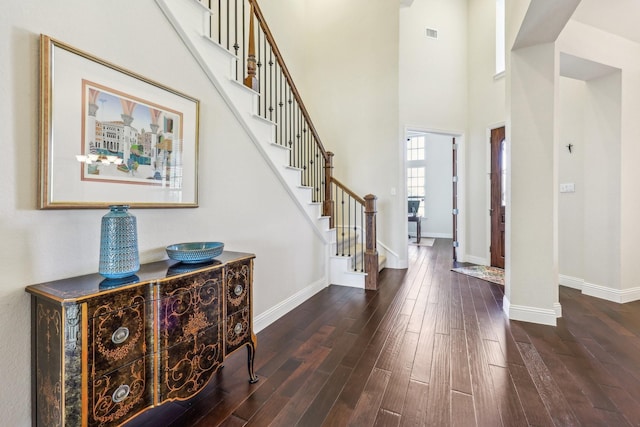 foyer entrance with dark hardwood / wood-style flooring and a towering ceiling