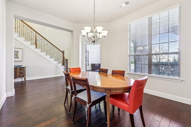 dining space with dark hardwood / wood-style flooring and an inviting chandelier