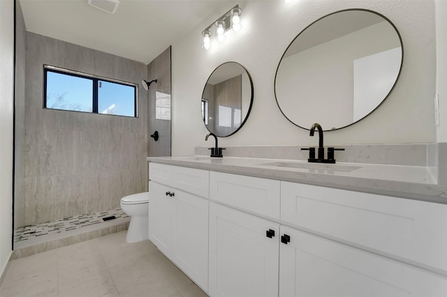 bathroom with tile patterned floors, toilet, a tile shower, and vanity