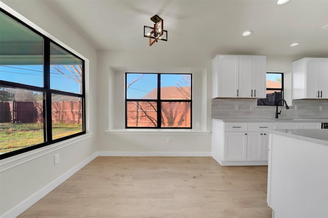 kitchen with tasteful backsplash, sink, white cabinets, and plenty of natural light