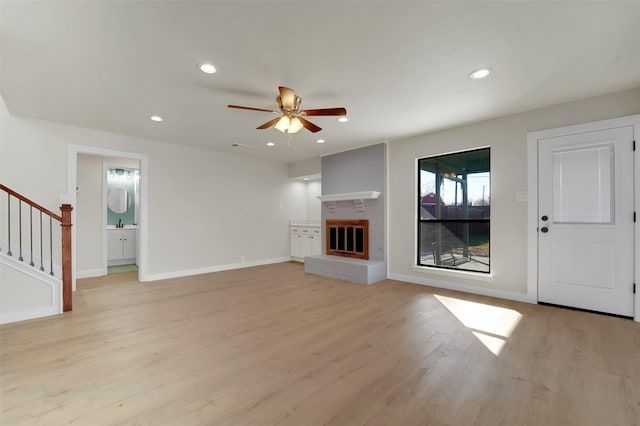 unfurnished living room featuring a fireplace, light hardwood / wood-style flooring, and ceiling fan