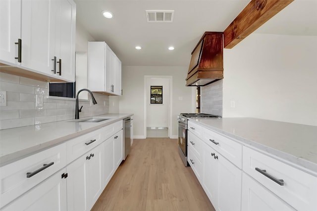 kitchen with decorative backsplash, appliances with stainless steel finishes, white cabinets, and sink