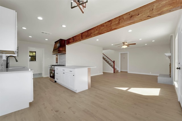 kitchen with ceiling fan, sink, stainless steel stove, custom exhaust hood, and light wood-type flooring