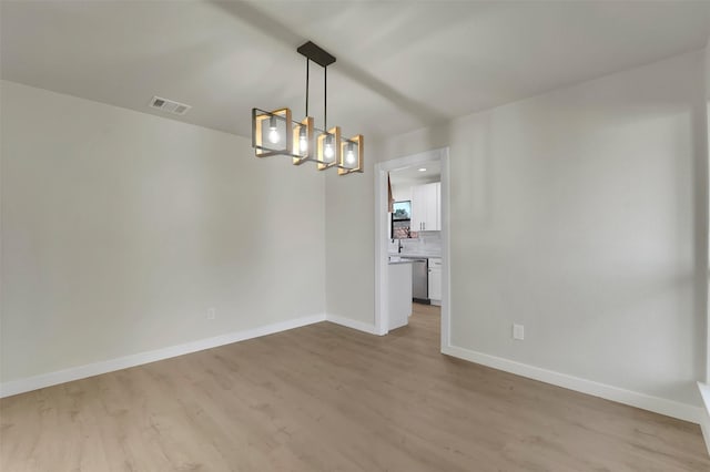 spare room featuring light hardwood / wood-style floors and a chandelier