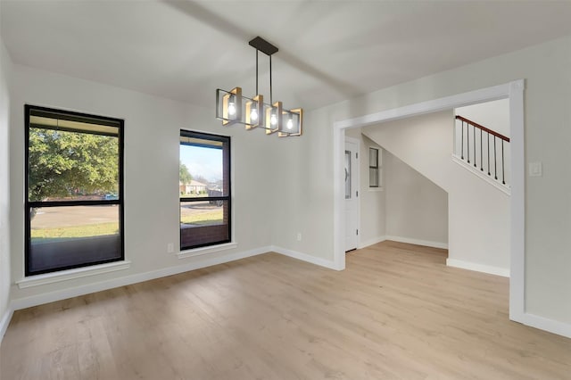 unfurnished room featuring a notable chandelier and light hardwood / wood-style flooring