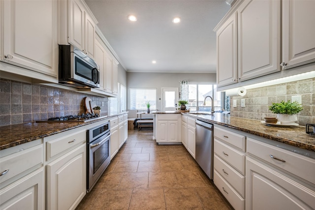 kitchen with sink, dark stone countertops, white cabinetry, and stainless steel appliances