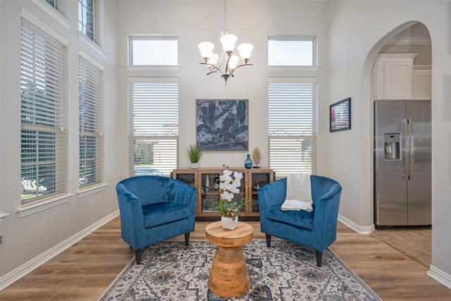 living area with wood-type flooring, an inviting chandelier, and a high ceiling