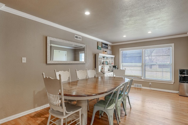 dining space with crown molding, a textured ceiling, and light wood-type flooring