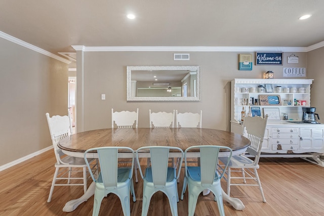 dining area with crown molding and light hardwood / wood-style flooring