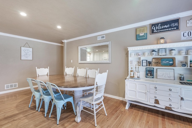 dining space with light hardwood / wood-style flooring and ornamental molding