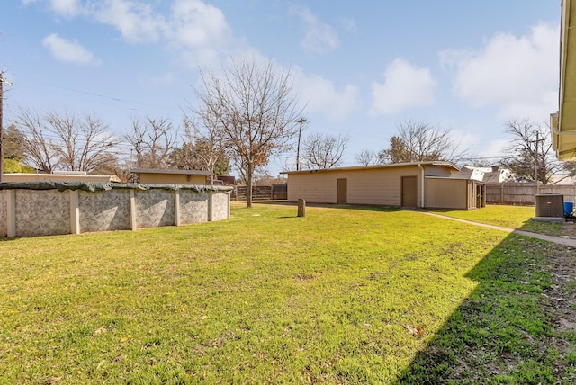 view of yard featuring central AC unit, a storage unit, and a covered pool