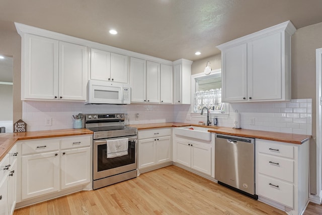 kitchen featuring white cabinets, stainless steel appliances, butcher block counters, and sink