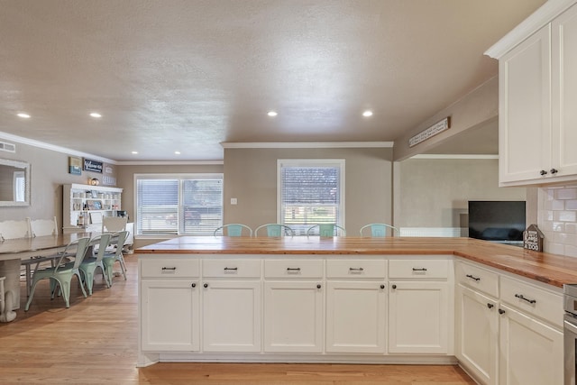 kitchen featuring wood counters, tasteful backsplash, kitchen peninsula, light hardwood / wood-style floors, and white cabinets