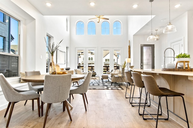 dining area with ceiling fan, french doors, a healthy amount of sunlight, and light wood-type flooring