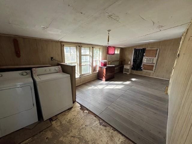 washroom featuring cooling unit, washing machine and clothes dryer, light hardwood / wood-style floors, and wood walls