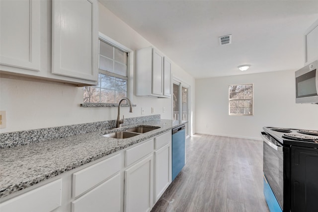 kitchen with sink, stainless steel appliances, light stone countertops, white cabinets, and light wood-type flooring