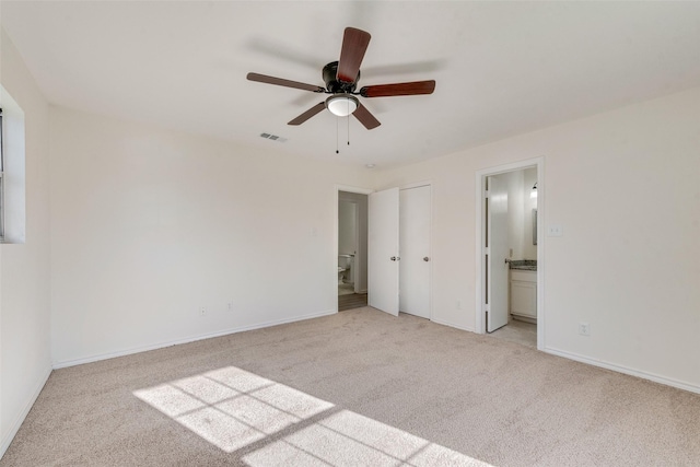 unfurnished bedroom featuring ceiling fan, light colored carpet, and connected bathroom