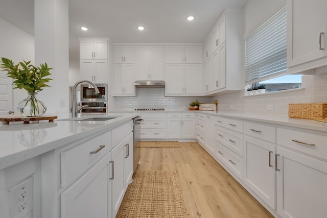 kitchen featuring light stone countertops, cooktop, sink, light hardwood / wood-style floors, and white cabinetry