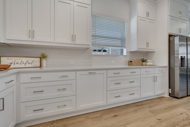 kitchen with white cabinets, stainless steel refrigerator with ice dispenser, tasteful backsplash, and light hardwood / wood-style flooring