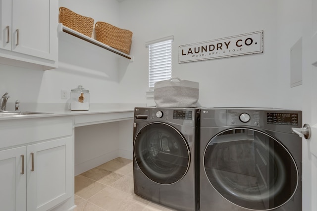 laundry room featuring cabinets, light tile patterned floors, washing machine and clothes dryer, and sink