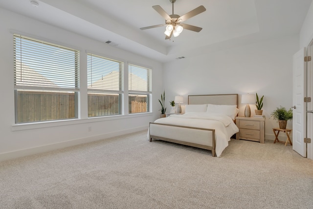 carpeted bedroom with a tray ceiling and ceiling fan