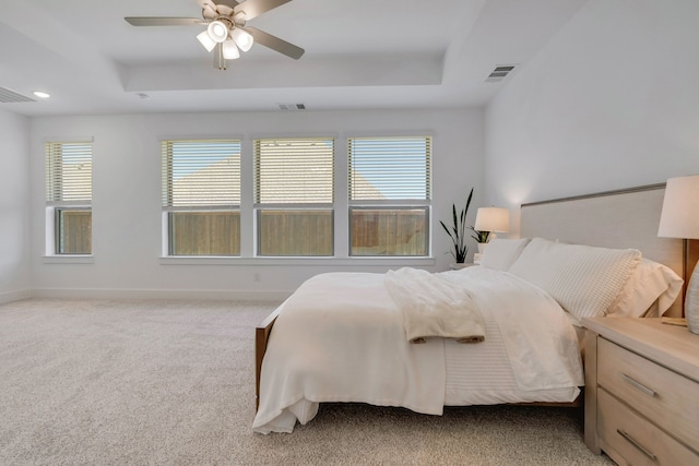 bedroom featuring ceiling fan, a raised ceiling, and light colored carpet