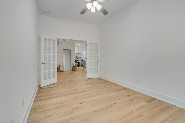 empty room with ceiling fan, light hardwood / wood-style floors, and french doors