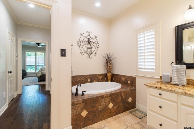 bathroom with vanity, ceiling fan, crown molding, and tiled tub