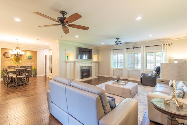 living room featuring crown molding, ceiling fan with notable chandelier, hardwood / wood-style floors, and a fireplace