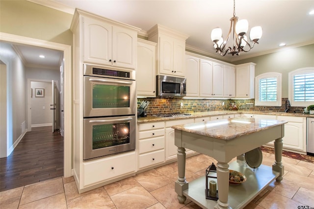 kitchen with light stone countertops, hanging light fixtures, stainless steel appliances, a notable chandelier, and decorative backsplash