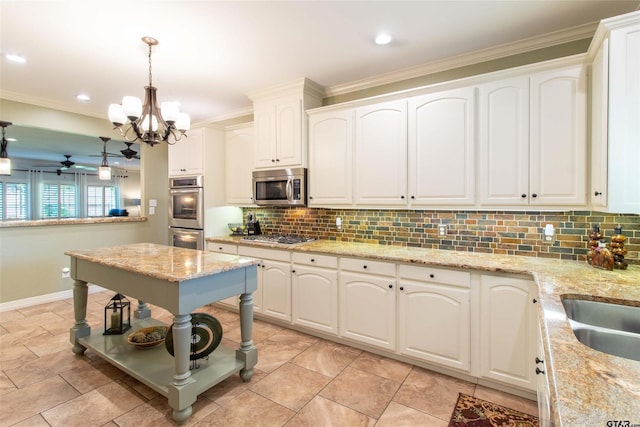 kitchen featuring pendant lighting, ceiling fan with notable chandelier, appliances with stainless steel finishes, light stone counters, and white cabinetry