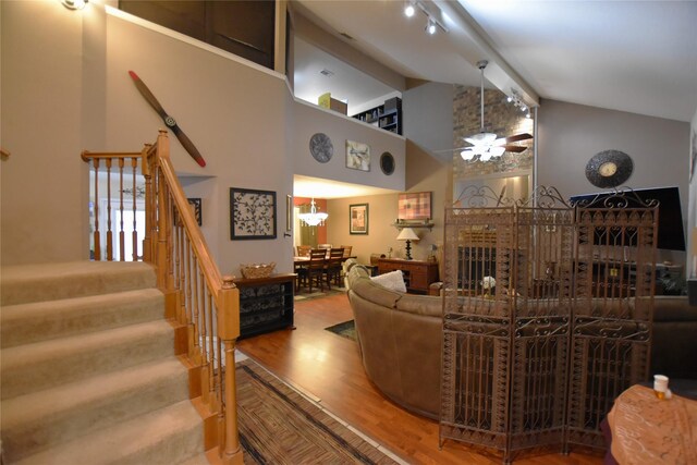 living room featuring a brick fireplace, ceiling fan, beam ceiling, high vaulted ceiling, and hardwood / wood-style floors