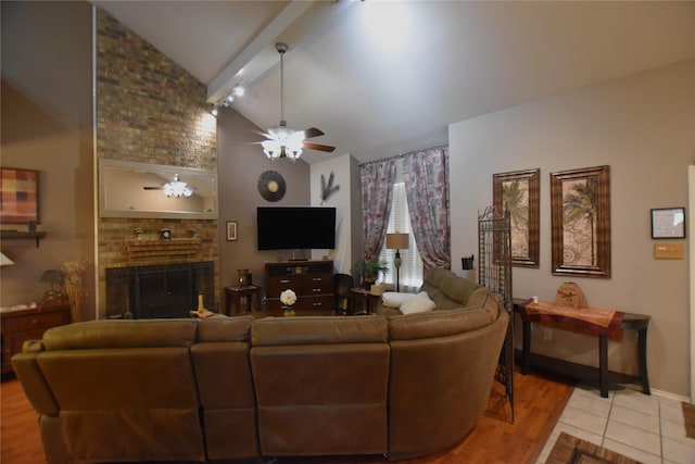 living room featuring ceiling fan, a brick fireplace, light hardwood / wood-style flooring, beamed ceiling, and high vaulted ceiling