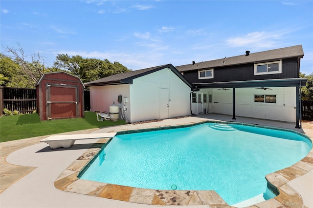 view of pool with ceiling fan, a diving board, a storage shed, and a patio