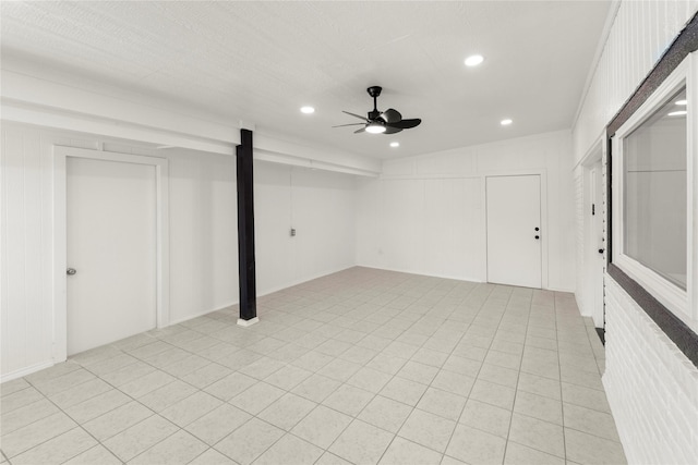 basement with ceiling fan and light tile patterned floors